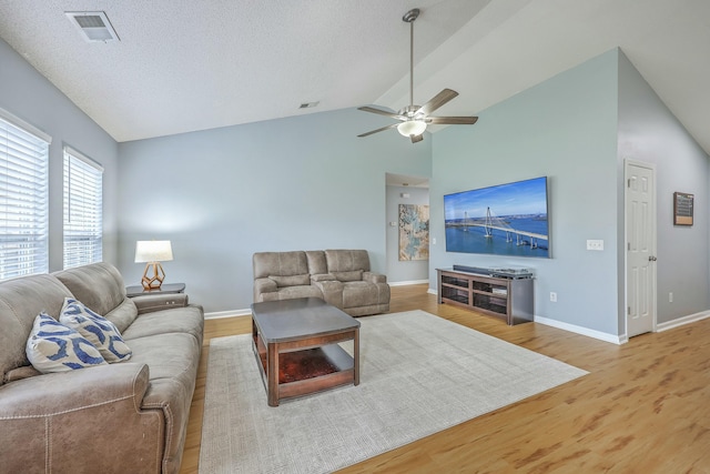 living area featuring visible vents, wood finished floors, a ceiling fan, and vaulted ceiling