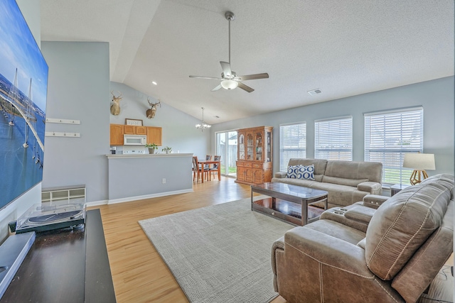 living area with wood finished floors, ceiling fan with notable chandelier, visible vents, and a wealth of natural light