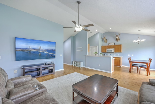 living room featuring ceiling fan with notable chandelier, baseboards, light wood finished floors, and high vaulted ceiling