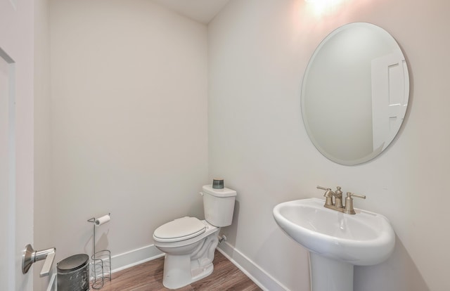 bathroom with toilet, wood-type flooring, and sink