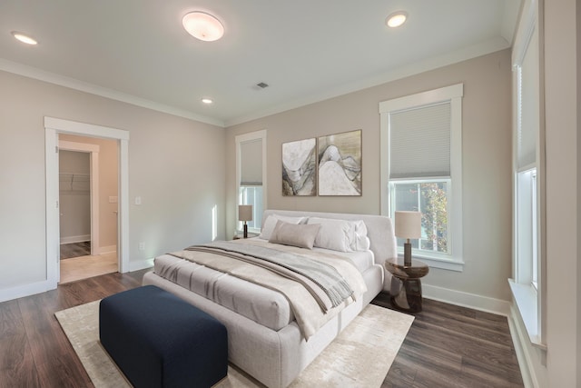 bedroom featuring a spacious closet, dark hardwood / wood-style floors, a closet, and crown molding