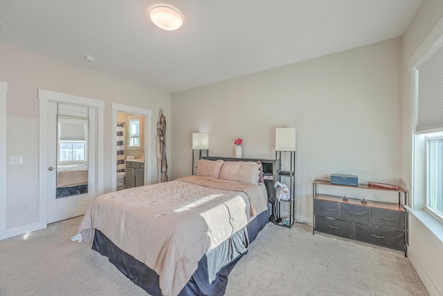 bedroom featuring multiple windows, connected bathroom, and light colored carpet