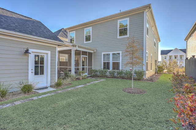 rear view of house featuring a yard and a sunroom