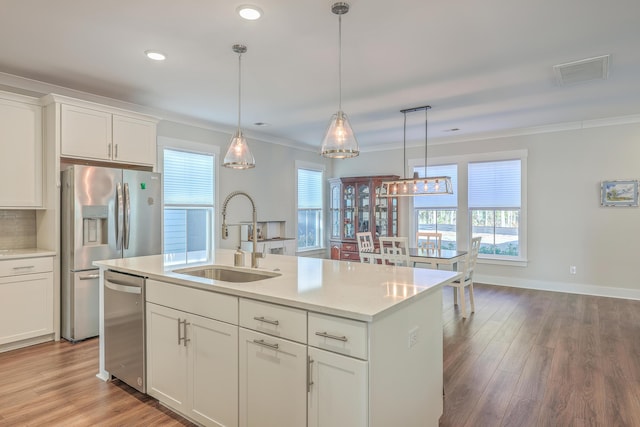 kitchen with appliances with stainless steel finishes, a kitchen island with sink, white cabinets, and sink