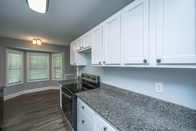 kitchen with stainless steel electric stove, white cabinetry, dark wood-style flooring, dark stone countertops, and baseboards