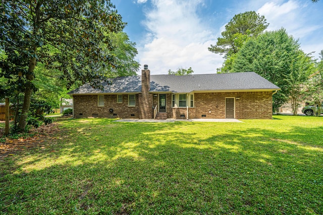 rear view of house featuring crawl space, a patio, a chimney, a yard, and brick siding