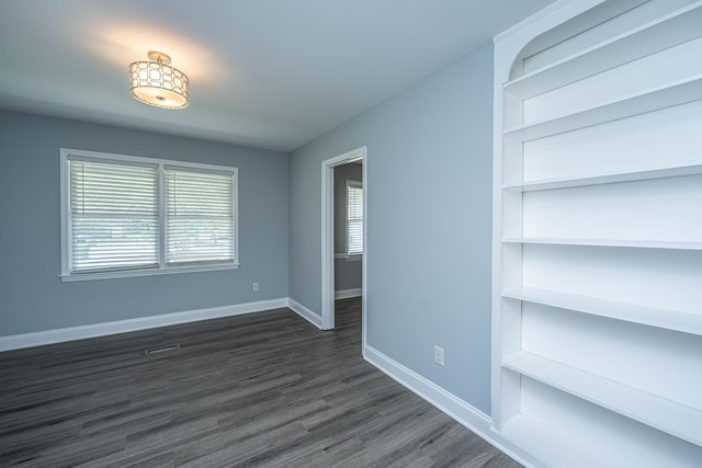 unfurnished room featuring baseboards and dark wood-type flooring