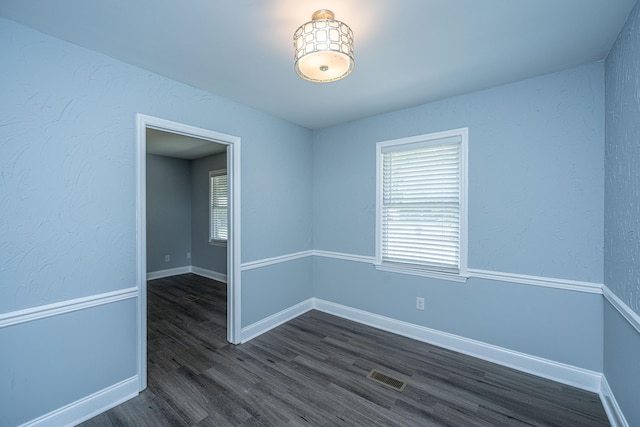 empty room with dark wood finished floors and baseboards
