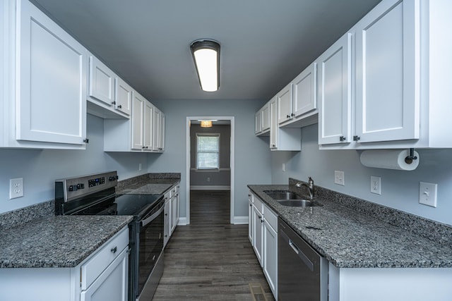 kitchen with appliances with stainless steel finishes, a sink, baseboards, and white cabinetry