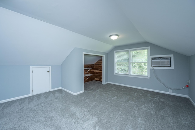 additional living space featuring carpet flooring, baseboards, lofted ceiling, and a wall mounted AC