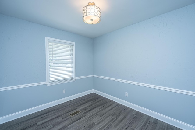 spare room featuring dark wood-style flooring and baseboards