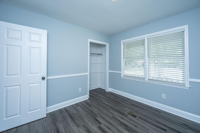 unfurnished bedroom featuring dark wood-style flooring, baseboards, and a closet