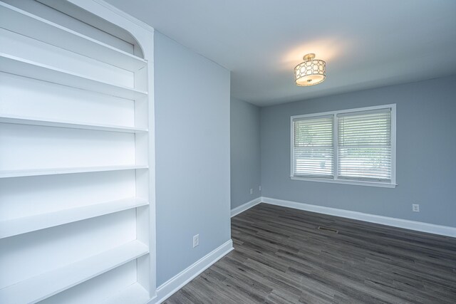 unfurnished dining area with baseboards and dark wood finished floors