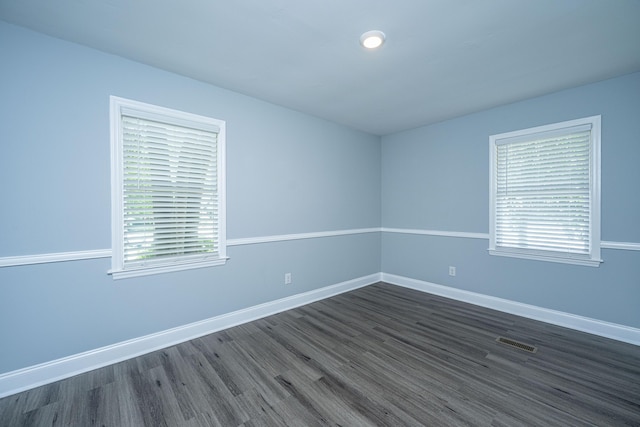 spare room featuring dark wood-style flooring and baseboards