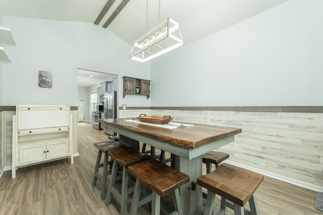 dining area featuring beamed ceiling, high vaulted ceiling, and hardwood / wood-style flooring