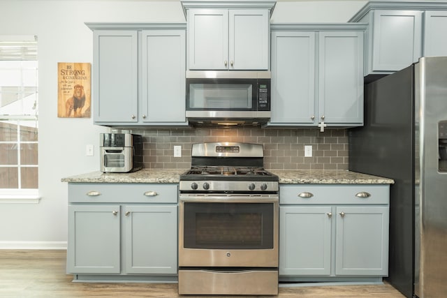 kitchen with light stone counters, tasteful backsplash, and appliances with stainless steel finishes