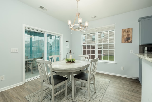 dining area with wood-type flooring and an inviting chandelier