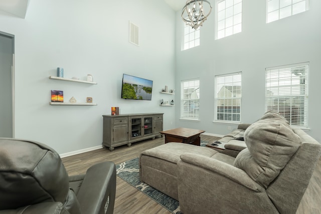 living room featuring hardwood / wood-style flooring, a high ceiling, and a notable chandelier