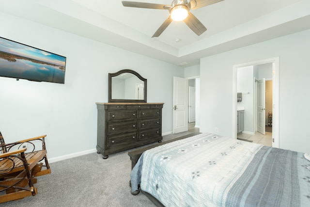 carpeted bedroom with ceiling fan, ensuite bathroom, and a tray ceiling