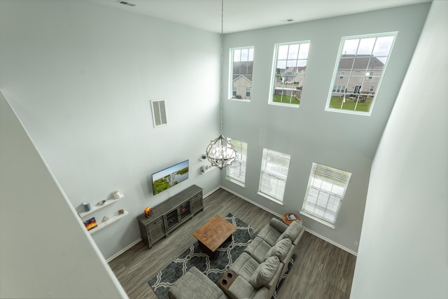 living room with wood-type flooring, a towering ceiling, and a notable chandelier