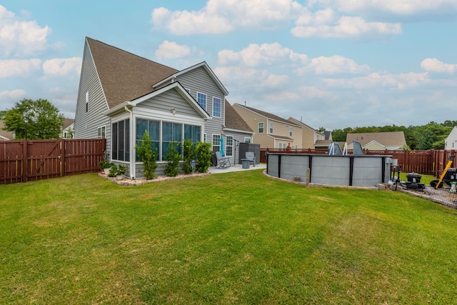 back of property featuring a fenced in pool, a sunroom, and a lawn