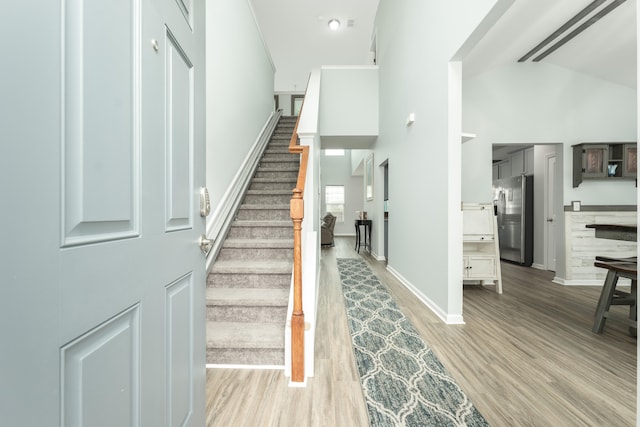 stairway with wood-type flooring and high vaulted ceiling