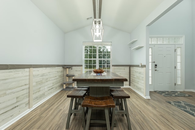 dining area with wood-type flooring, wooden walls, and vaulted ceiling with beams