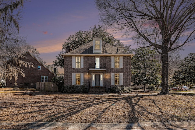 colonial inspired home with fence and brick siding