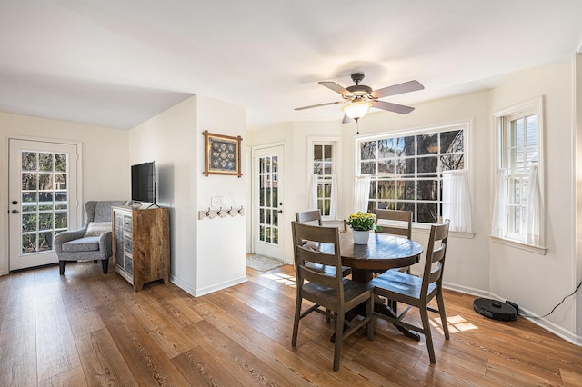 dining room with a ceiling fan, baseboards, and hardwood / wood-style floors