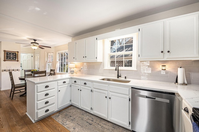 kitchen with a peninsula, dark wood-type flooring, a sink, dishwasher, and tasteful backsplash