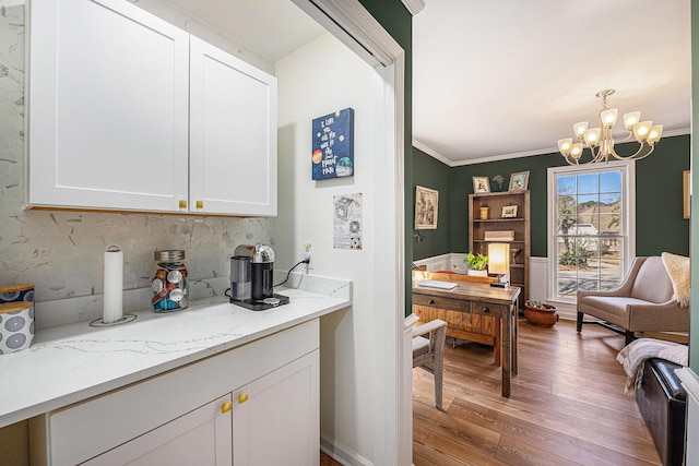 kitchen featuring tasteful backsplash, a chandelier, ornamental molding, light wood-type flooring, and white cabinetry