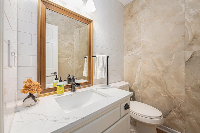 bathroom with toilet, vanity, and tile walls