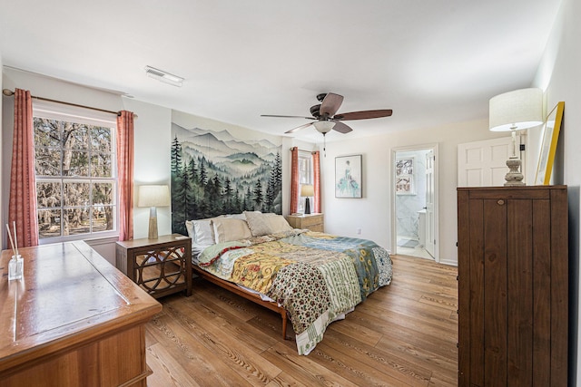 bedroom featuring light wood-style flooring, visible vents, ceiling fan, and connected bathroom