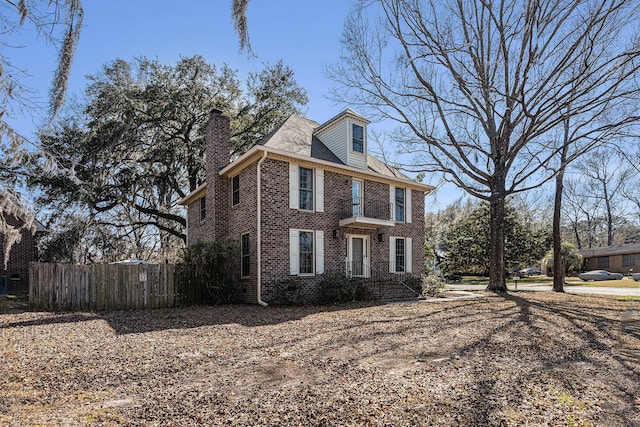 view of home's exterior featuring brick siding, fence, and a chimney