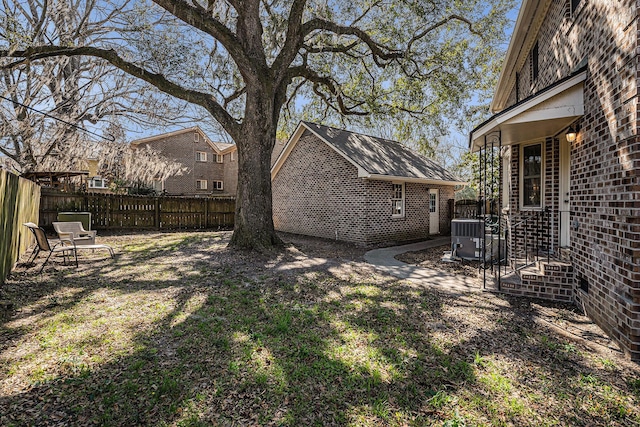 view of yard featuring fence, an outdoor structure, and central AC unit