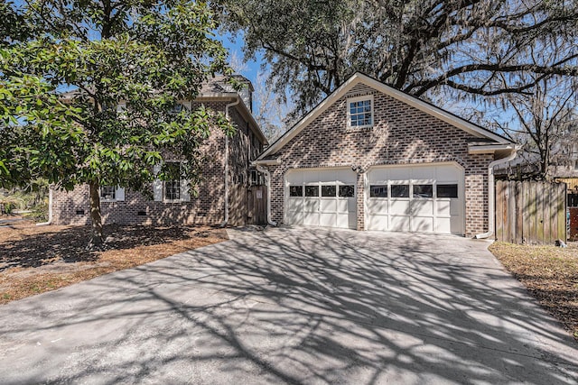 view of front of house with driveway, an attached garage, fence, and brick siding