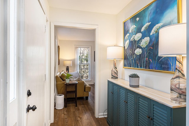 corridor with dark wood-type flooring and baseboards