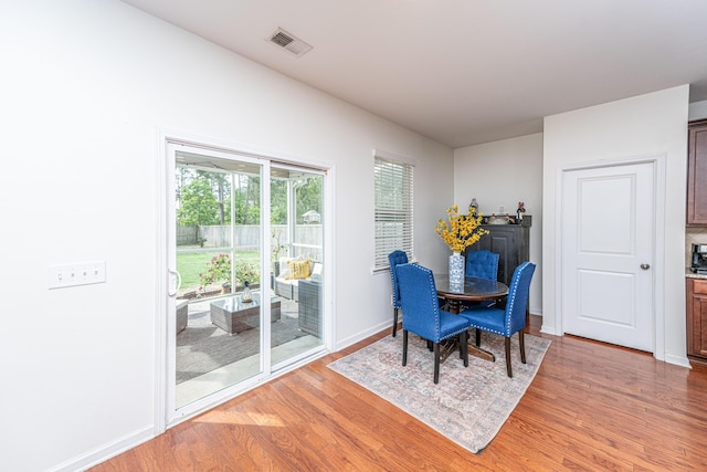 dining area with baseboards, light wood-style flooring, and visible vents