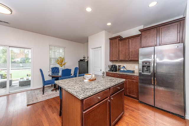 kitchen with visible vents, light wood-type flooring, light stone counters, and stainless steel fridge with ice dispenser
