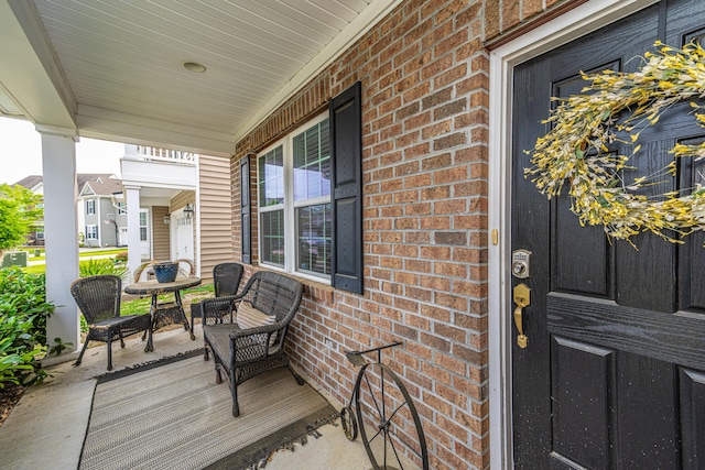view of exterior entry with a porch and brick siding