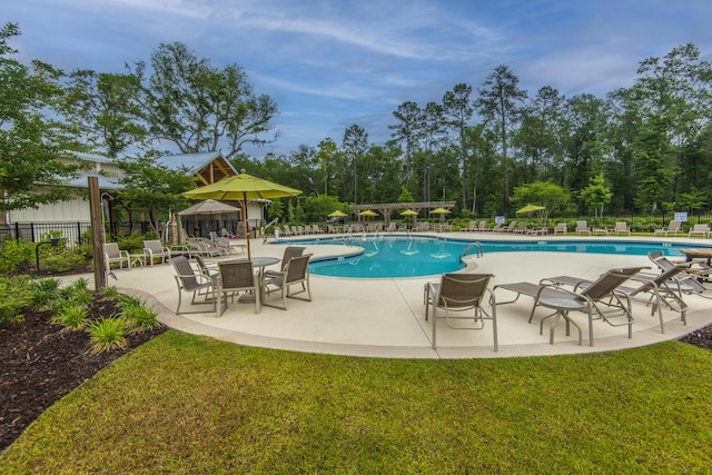 community pool with fence, a patio, and a lawn