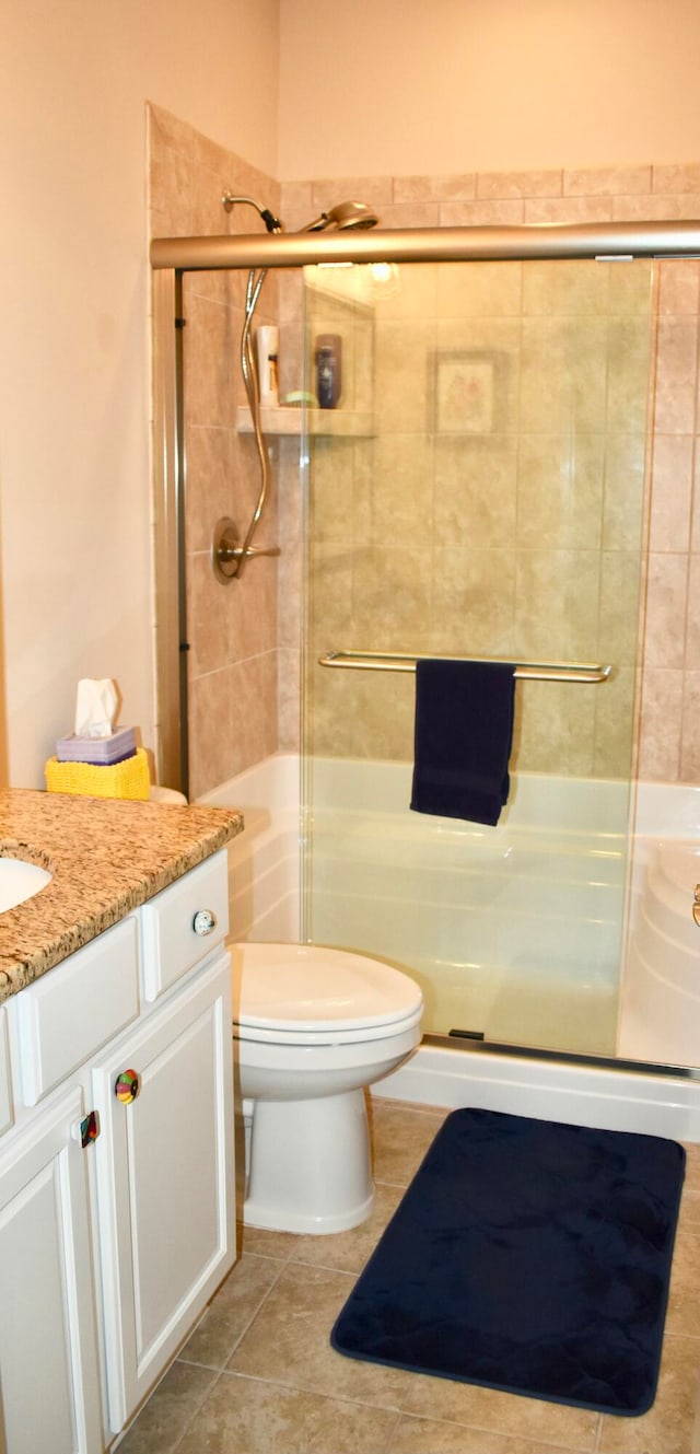 bathroom featuring tile patterned floors, vanity, an enclosed shower, and toilet