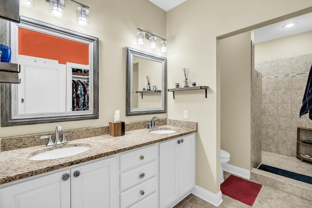 bathroom featuring toilet, tile patterned flooring, vanity, and tiled shower