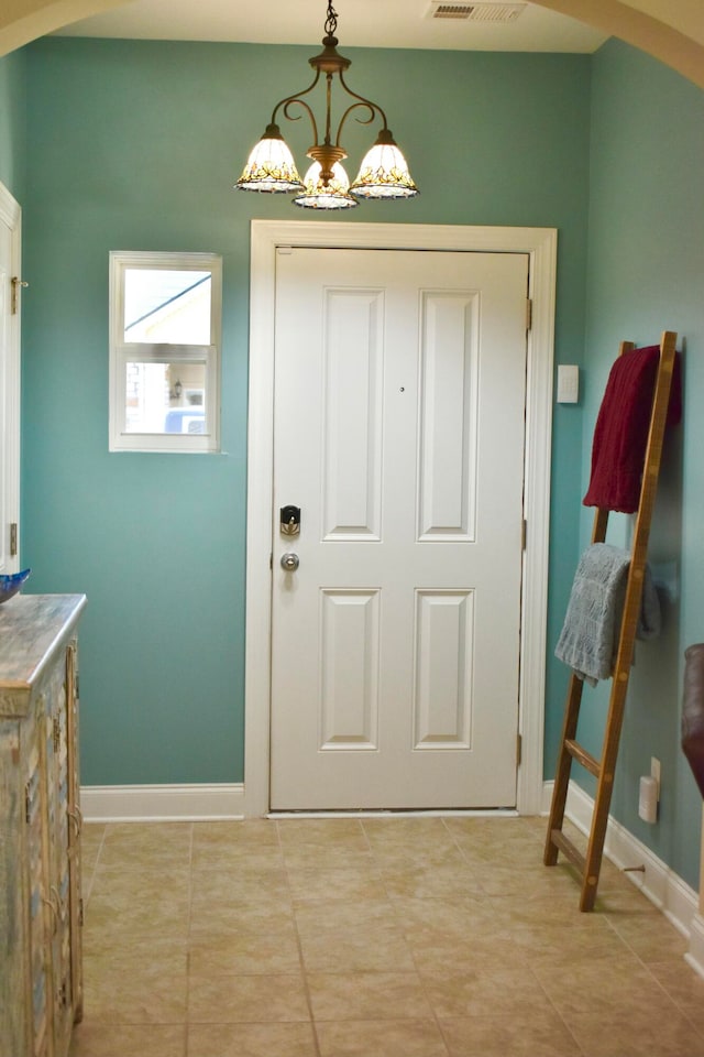 entryway with light tile patterned flooring and a notable chandelier