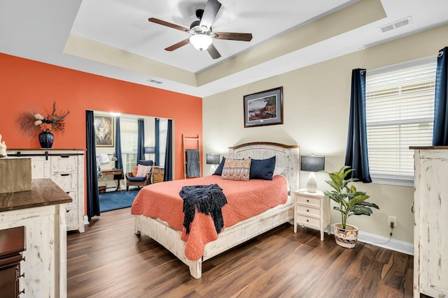 bedroom featuring a tray ceiling, ceiling fan, and dark hardwood / wood-style floors