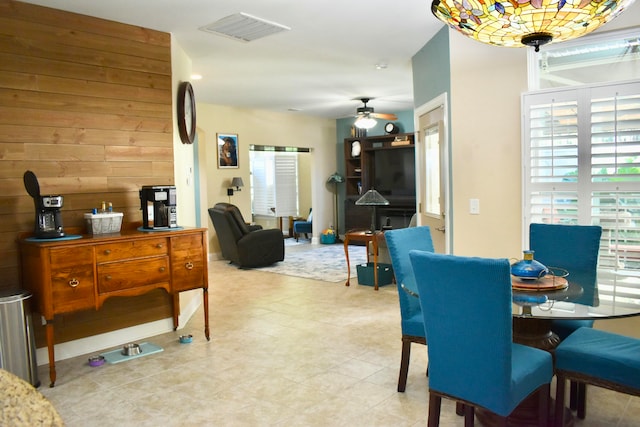 dining space featuring wood walls and ceiling fan