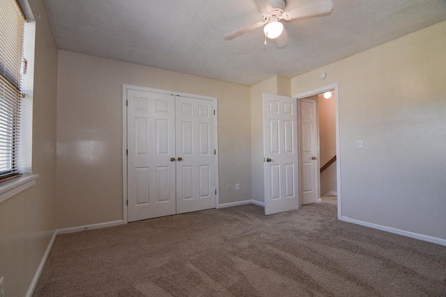 unfurnished bedroom featuring a textured ceiling, ceiling fan, light colored carpet, and a closet