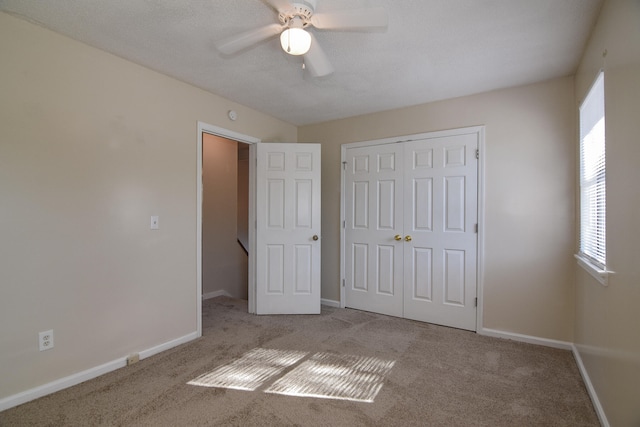 unfurnished bedroom featuring a closet, ceiling fan, light colored carpet, and a textured ceiling