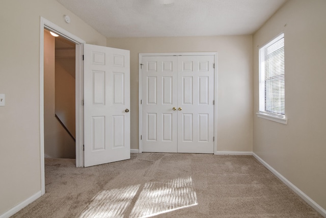 unfurnished bedroom with a textured ceiling and light colored carpet