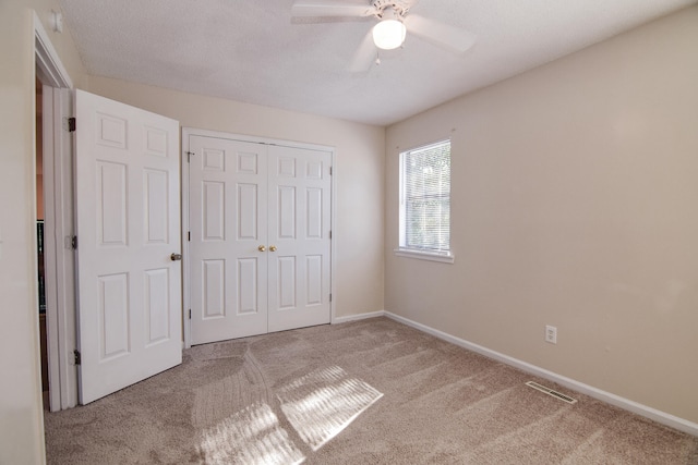 unfurnished bedroom with carpet floors, a textured ceiling, ceiling fan, and a closet